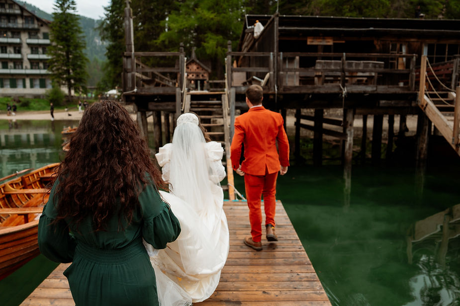 bride, groom, and officiant walk along dock at the Lago di Braies during italy elopement in the dolomites