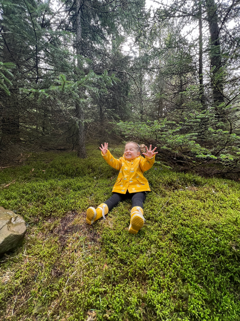 small kid sits on mossy ground while hiking in iceland