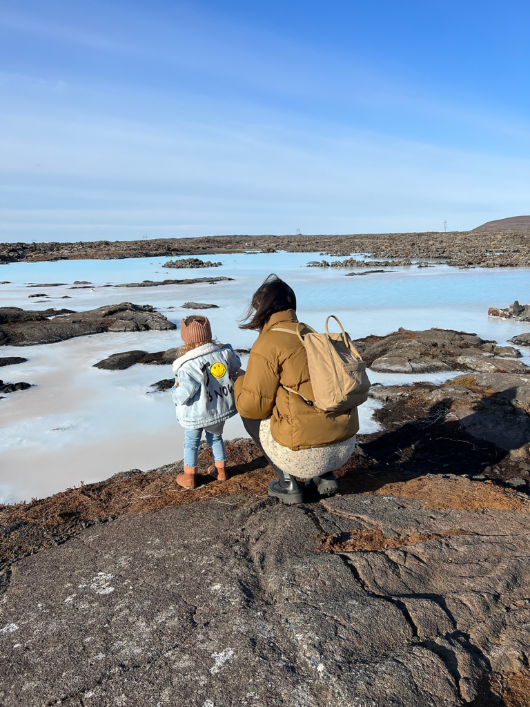 mom stands by the endge of the blue lagoon in iceland with her child