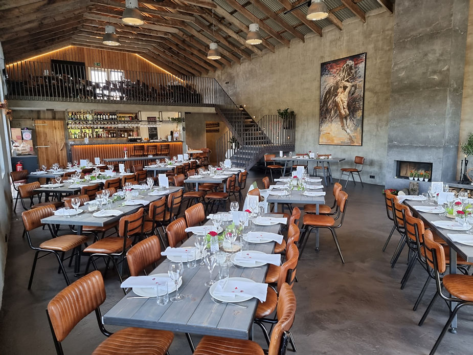 Rustic iceland wedding venue with set tables, brown leather chairs, and a stocked bar. A large painting adorns the wall, creating a warm, inviting mood.