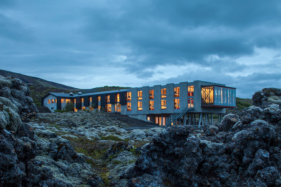 wedding venue with illuminated windows, set in a rocky, mossy landscape under a cloudy, blue evening sky, creates a serene, remote mood in iceland.