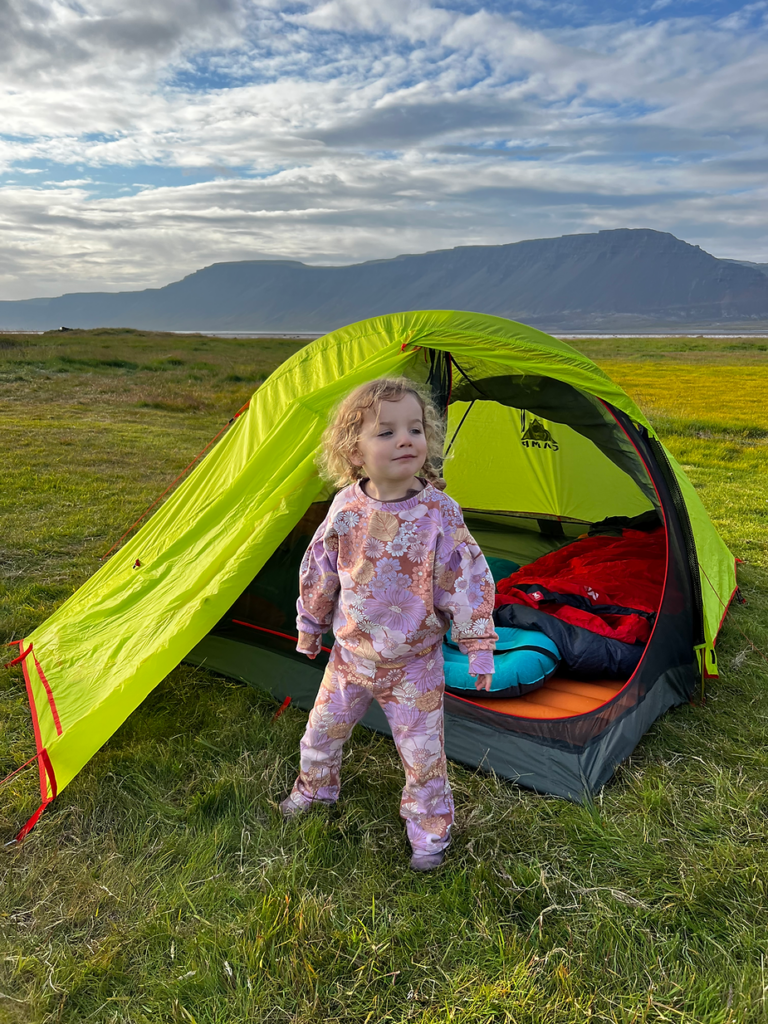 after knowing what to do in iceland with kids, a small girl stands outside of a tent