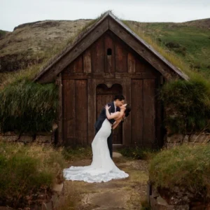 bride and groom kiss in front of turf house in iceland