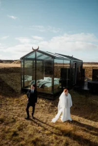 bride and groom stand in front of glass cabin before their iceland elopement