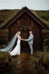 bride and groom stand in front of turf house during iceland elopement photos.