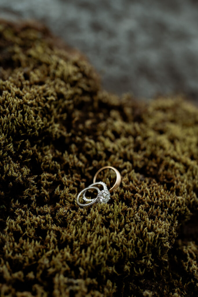 Two rings, one gold and one silver with a diamond, rest on green moss. Þórsmörk Valley in iceland.