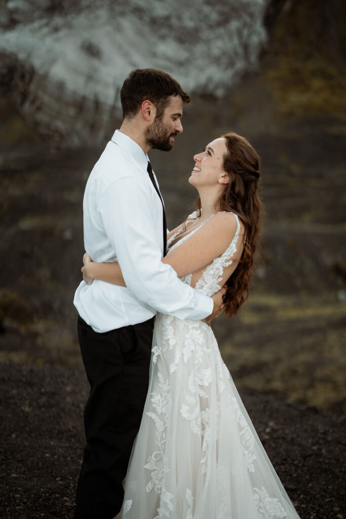 bride and groom embrace and smiles against a rocky mountain backdrop during elopement. Þórsmörk Valley in iceland