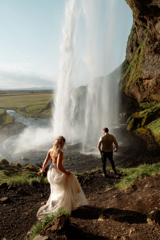 Bride and groom near a majestic waterfall, during iceland elopement with family.