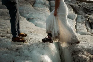 view of bride and grooms feet walking along a glacier while eloping at one of the best places to elope, Solheimajokull Glacier