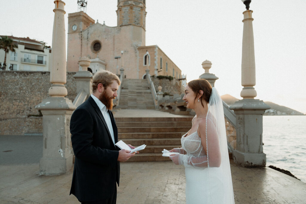 A bride and groom exchange vows by a historic church in Barcelona with stone steps during elopement.
