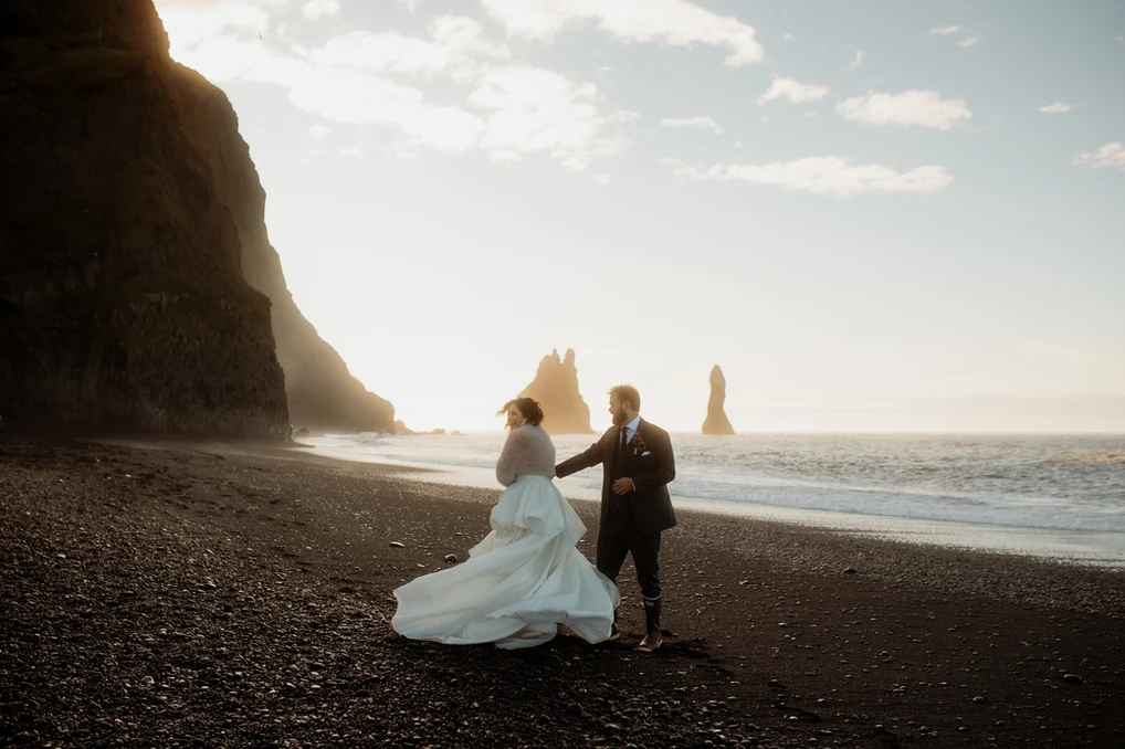 groom twirls bride during elopement photos on icelands black sand beach