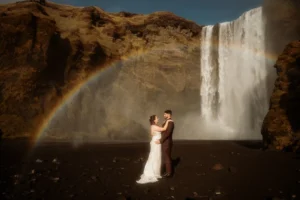 bride and groom embrace in front of one of icelands best places to elope, Skógafoss.