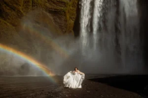 brides grabs elopement dress and stands in front of Skógafoss waterfall, a best place to elope in iceland
