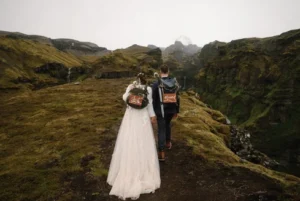 bride and groom hold hands and walk along landscape during iceland elopement