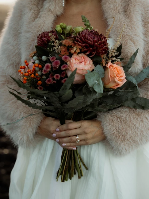 bride holds deep red and peach elopement bouquet