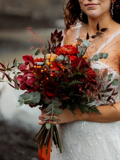 bride holds bright and and warm colored elopement bouquet