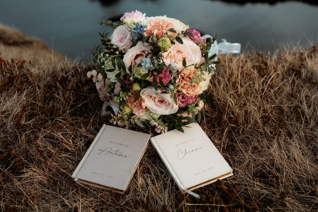 iceland elopement bouquet sits on grass beside wedding vow books