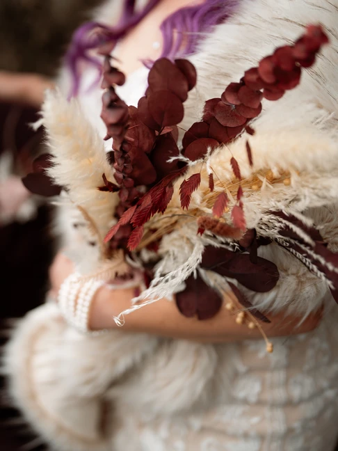 bride holds deep colorful elopement bouquet