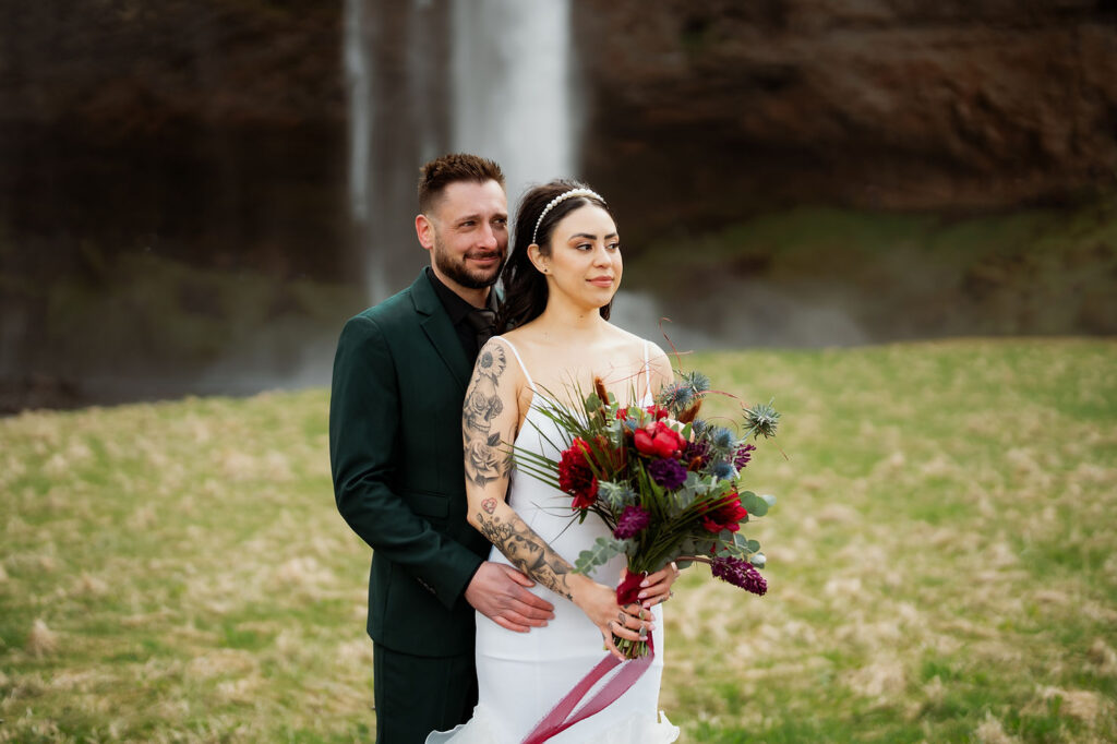 bride and groom pose for photos while holding iceland wedding flowers