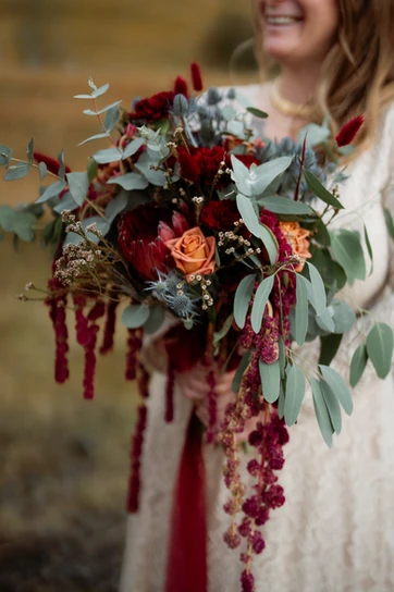 bride hold large red and green elopement bouquet for her iceland wedding