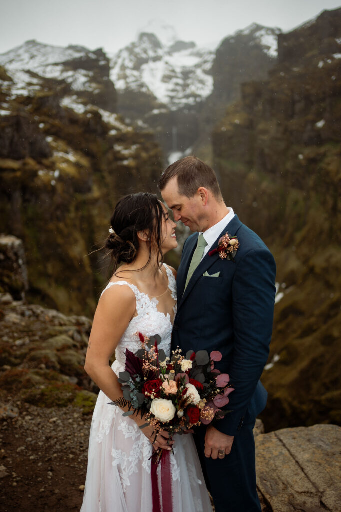 bride and groom stand in front of snowy gorge during iceland elopement photos