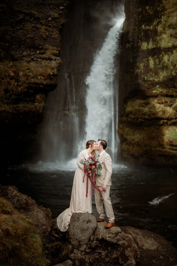 newly married couple stands on rock in front of waterfall, during iceland elopement