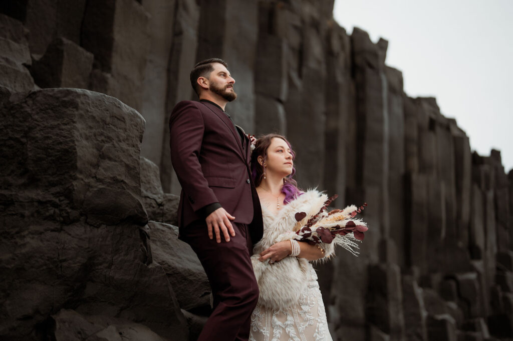bride and groom stand on basalt columns during iceland elopement