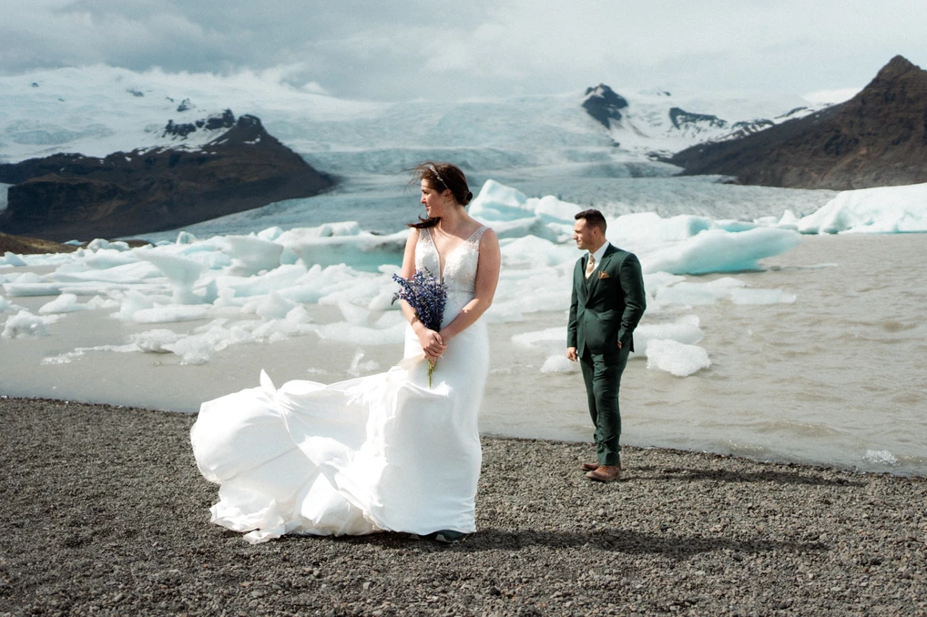 bride and groom stand on shore of glacier field in iceland during elopement