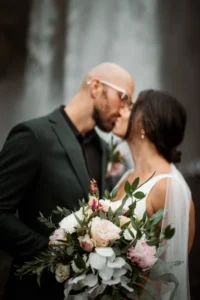 bride and groom kiss as they hold their elopement bouquet