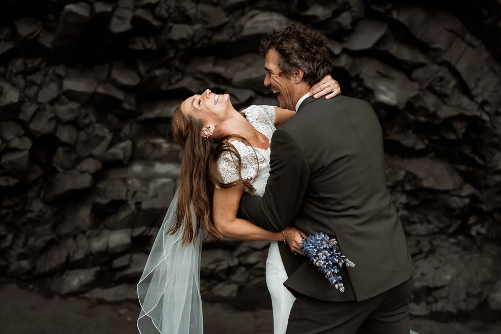 bride and groom smile and laugh holding a bouquet during iceland elopement