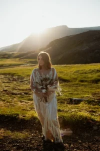 bride stands during golden hour holding wedding bouquet for iceland elopement