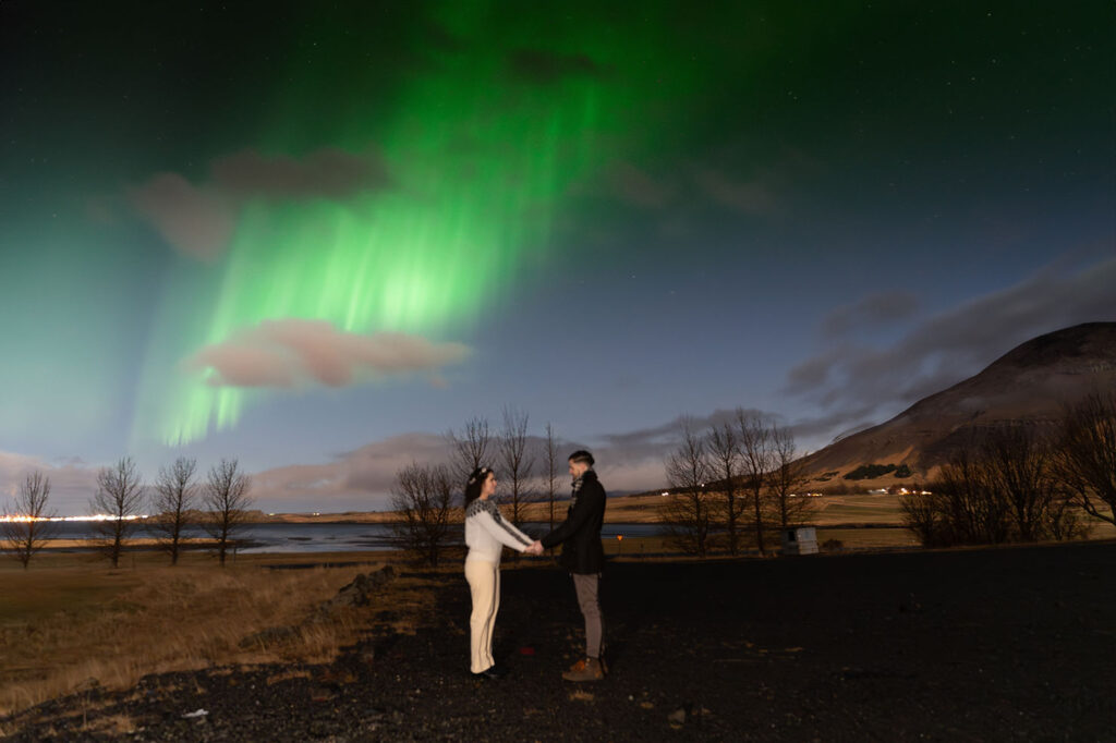 bride and groom in comfy clothes pose for photographer during northern lights elopement wedding in iceland