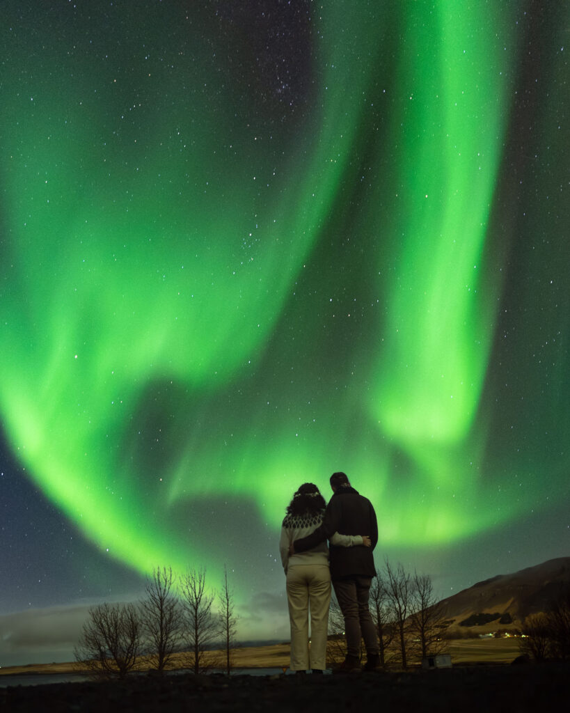 a couple stand in iceland under the northern lights for a proposal