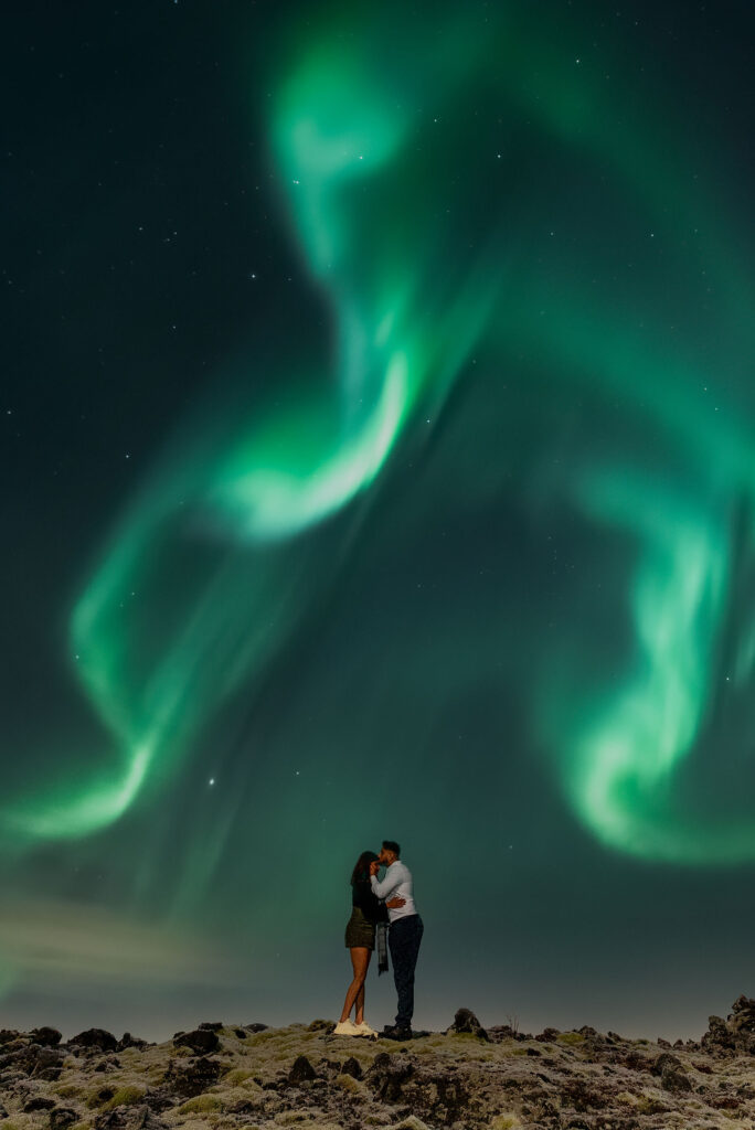 couple kisses each other during northern lights proposal in iceland