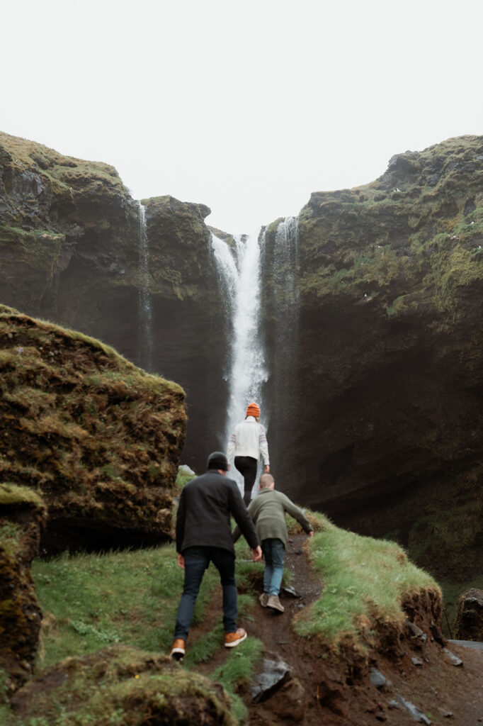 family hikes up to waterfall during family photos with iceland wedding photographer.