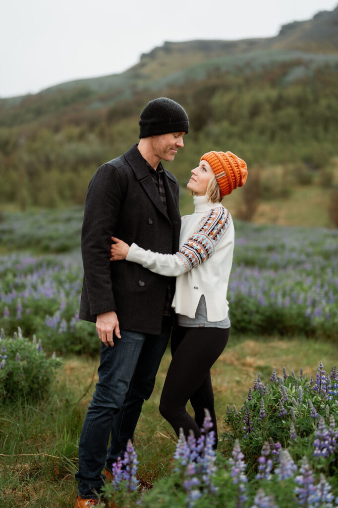 couple portrait standing in a field of flowers during Iceland family photo shoot.