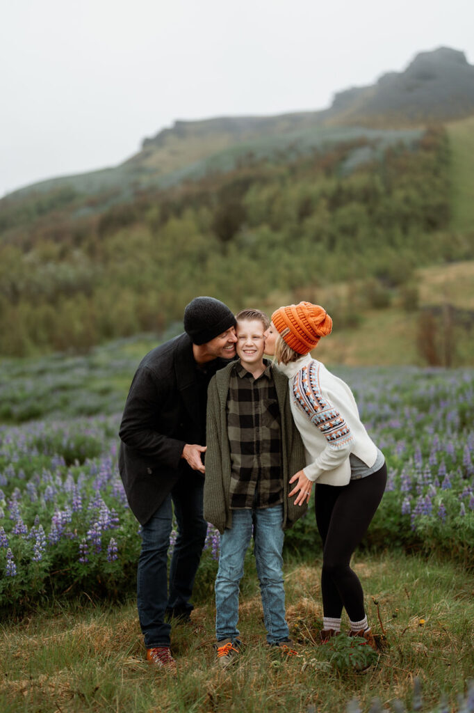 mom and dad kiss boy on the cheek during family photos with iceland wedding photographer.