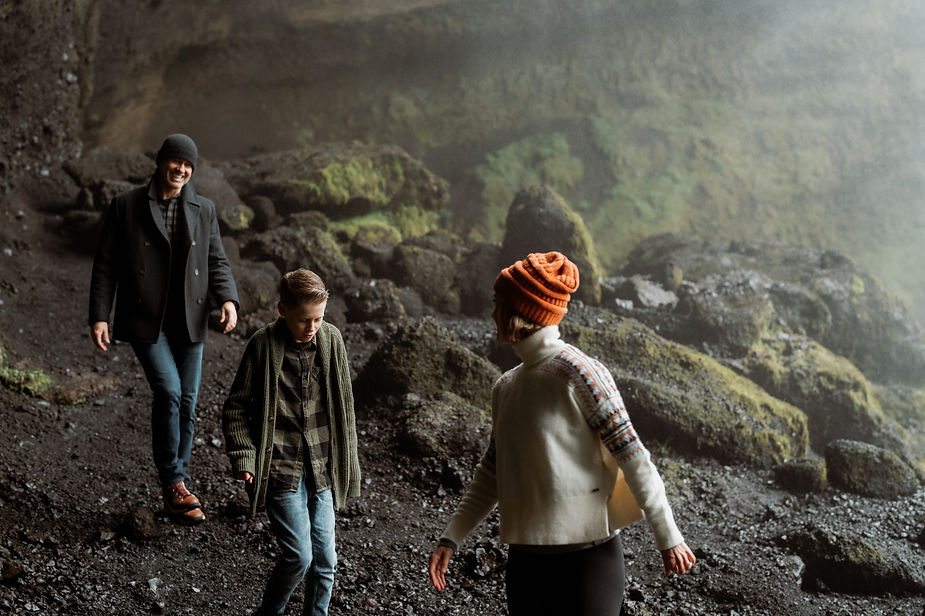 Family hikes behind waterfall during family photo shoot with iceland elopement photographer.