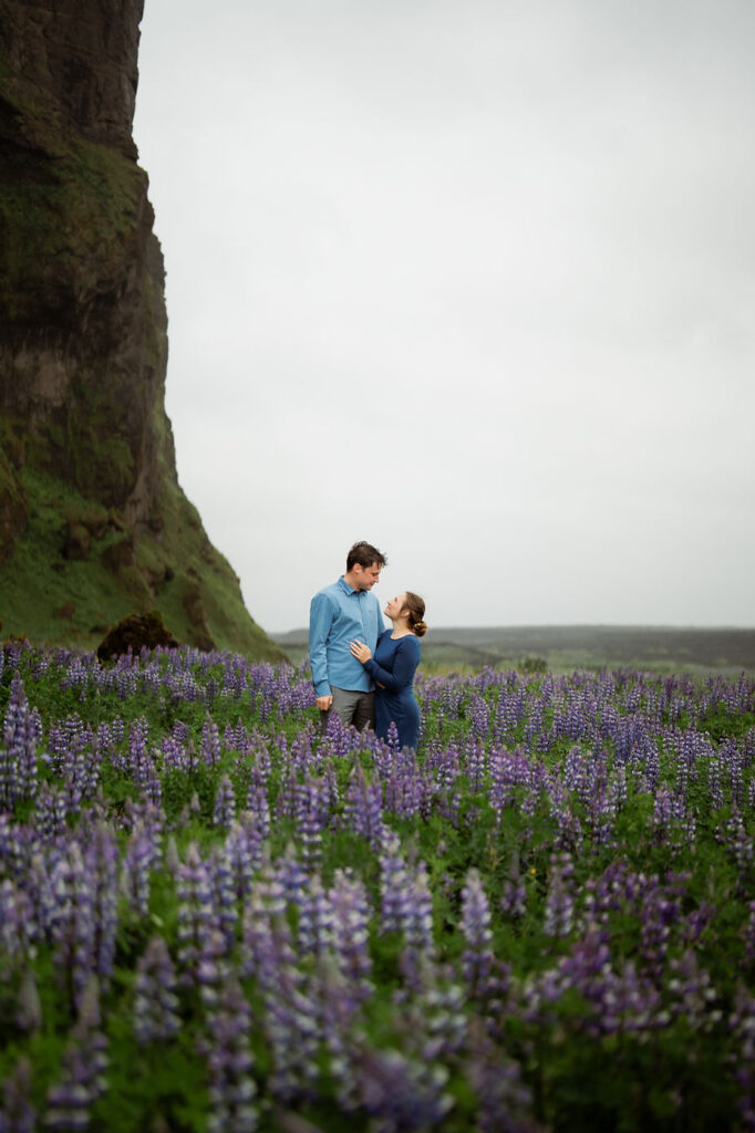 engaged couple stands in field of flowers during iceland summer engagement pictures.