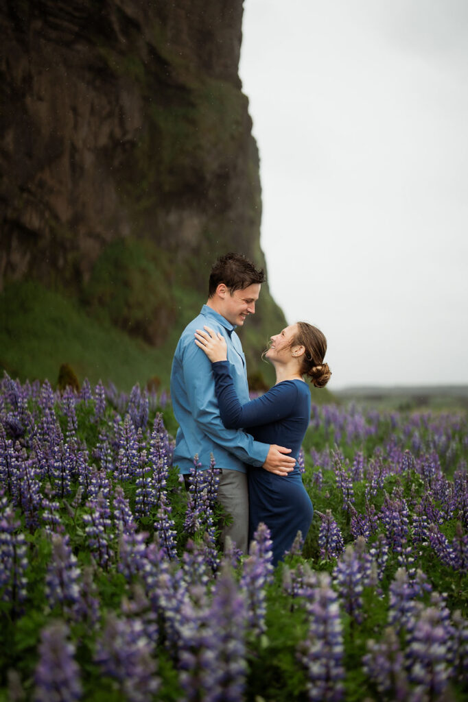 engaged couple pose in field of flowers for iceland elopement photographer.