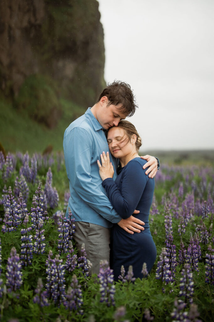 engaged couple hugs in a field of flowers during iceland proposal photo shoot.