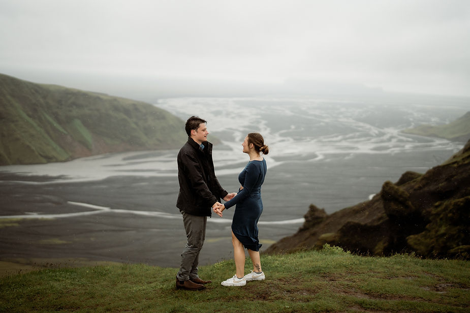 engaged couple holds hands with vast valley in the background during adventure engagement photo shoot in iceland.