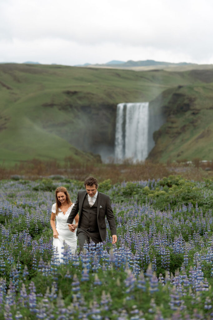 bride and groom walk through field of flowers during iceland wedding photos.