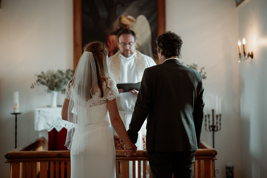 bride and groom stand in front of priest during iceland wedding ceremony.