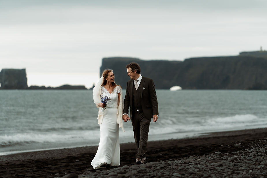 bride and groom walk on iceland coast during iceland adventure wedding photos.