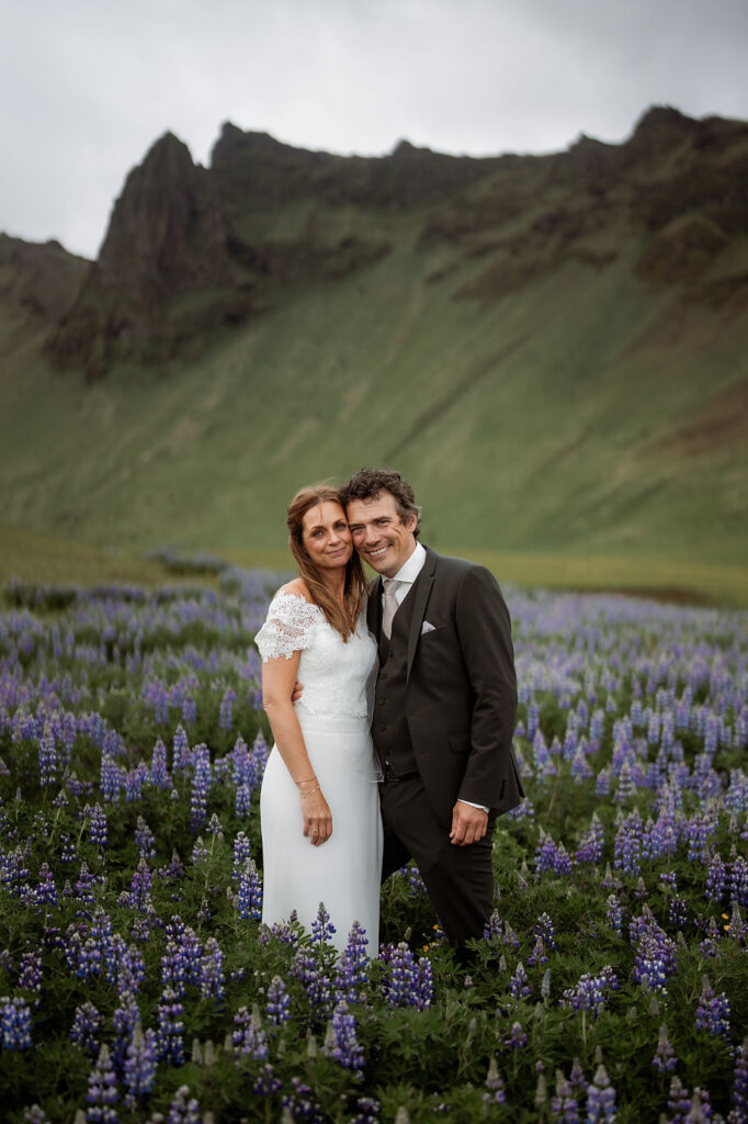 bride and groom stand in field of flowers during iceland wedding photos.