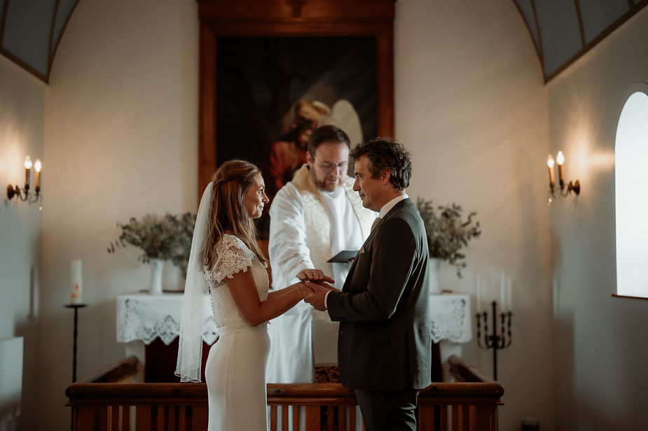 bride and groom in front of priest during church iceland wedding ceremony.