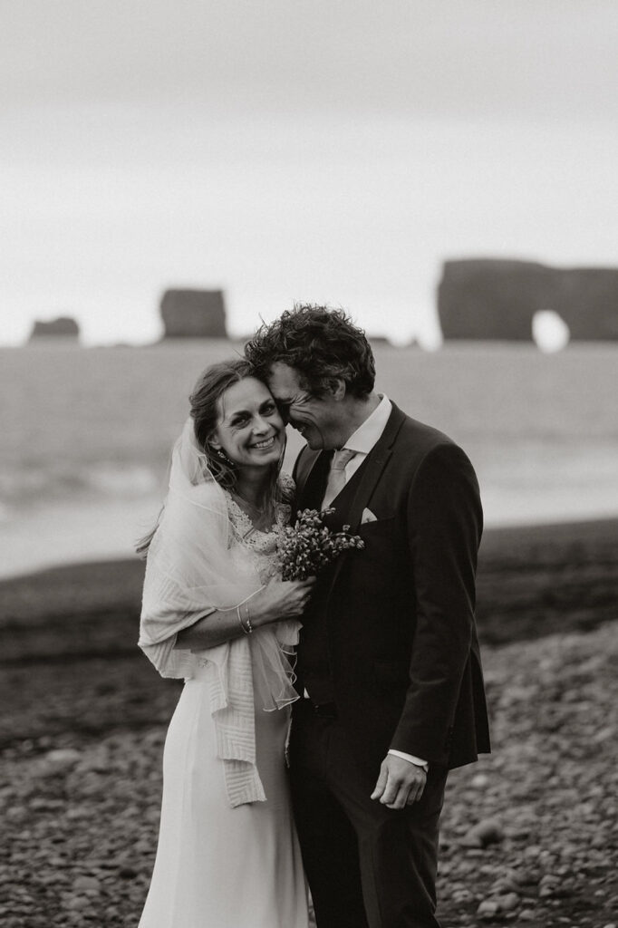 bride and groom smile and embrace each other during iceland coast wedding photos.