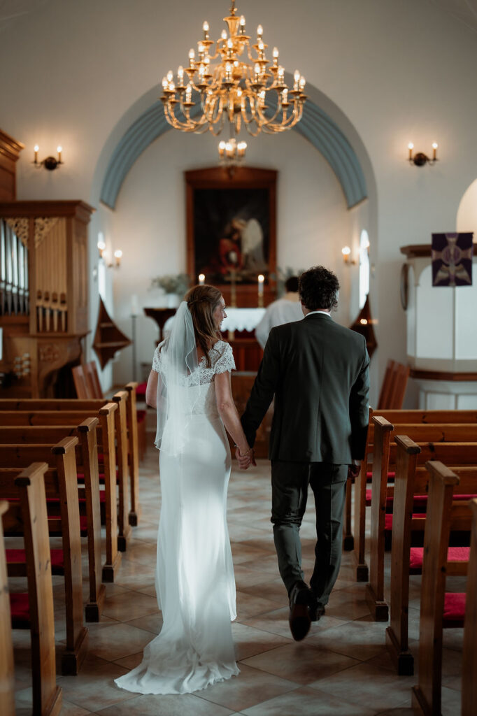 bride and groom walk up aisle during church Iceland wedding ceremony.