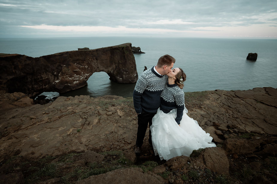 Bride and groom kiss on cliff edge during Iceland elopement adventure.